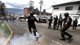 Un guardia nacional patea una bomba lacrimógena a los manifestantes