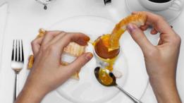 Una persona mojando un pedazo de pollo frito en una salsa