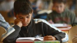 Niño lee un libro en una clase.