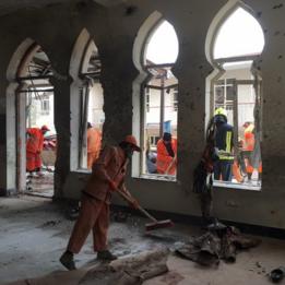 عمال أفغان ينظفون موقع الانفجار في المسجد