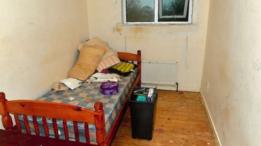 Habitación de la víctima con una cama pequeña y un tacho de basura.