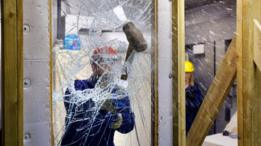 Un técnico rompiendo un vidrio con una mandarria