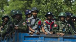 Policías y militares birmanos en camiones llegan a una aldea de la minoría rohingya