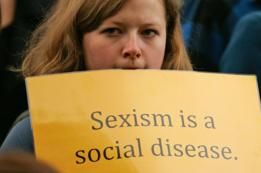 Mujer sostiene una pancarta que denuncia el sexismo.