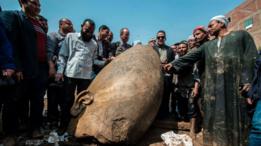El ministro de antigüedades egipcio y otros hombres posan junto a una porción de la estatua.