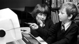 Dos niños frente a una computadora antigua
