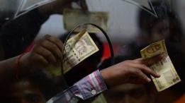 Manos con billetes en el mostrador de un banco