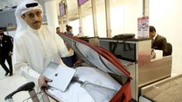 الناشط الكويتي ثامر بوراشد يضع حاسبه المحمول في حقيبة الأمتعة، قبل الصعود إلى الطائرة