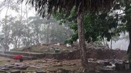 Restos de construcciones en piedra rodeados de árboles en el sitio arqueológico de Nim Li Punit