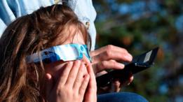 Una niña observa el eclipse con unos protectores solares puestos