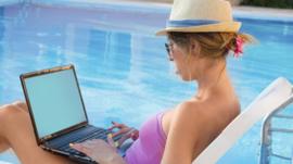 Woman on computer by pool