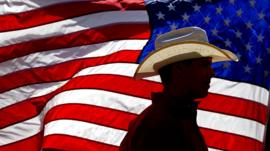 Man in a cowboy hat silhouetted against the US flag