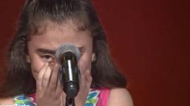 a girl crying in front of a microphone