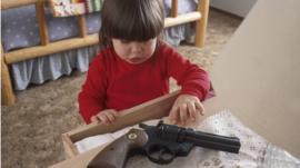 child reaching for gun