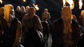 Masked men on horseback with flame torches