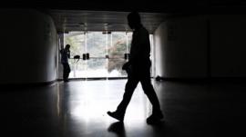 A security guard walks past an exit door as he waits for the power to return after a blackout during the FIBA Americas Championship basketball game between Paraguay and Dominican Republic in Caracas
