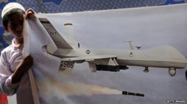 Pakistani youth holds a banner of US drone during a protest