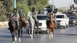 Militant Islamist fighters ride horses as they take part in a military parade along the streets of Raqqa, northern Syria, 30 June 2014