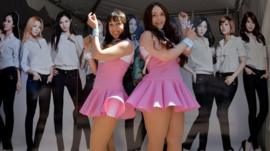 American fans of K-Pop in front of a poster for a girl band from South Korea