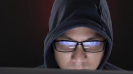 Shifty-looking man in front of computer screen