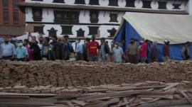 A tent and a group of people beside it in front of some bricks