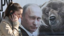 Woman walks past poster of Putin in Moscow