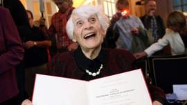 Ingeborg Syllm-Rapoport holds up her doctoral certificate