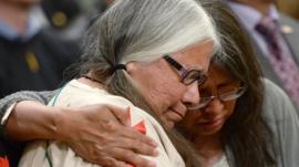 A woman is comforted in the audience during the closing ceremony of Commission