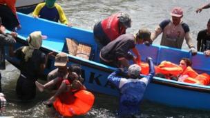 Rescuers assist survivors arriving on fishing boat at the wharf of Cidaun, West Java on July 24, 2013 after an Australia-bound boat carrying asylum-seekers sank off the Indonesian coast