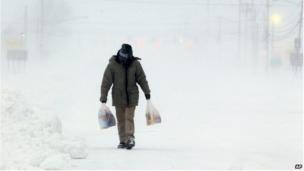 A man walks down a snow covered street in Hamburg, New York on 7 January 2014