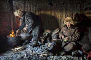 Herders keep warm in a hut on their mountainous migration route - copyright Timothy Allen