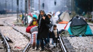A woman and three children walk on railway tracks connecting Greece with western Europe at the Greek-Macedonian border near the Greek village of Idomeni on 9 March, 2016