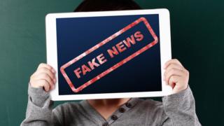 Boy holding fake news tablet