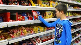 Boy being tempted by chocolates in a supermarket
