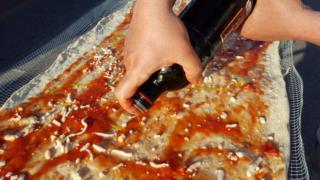 Olive being poured on to the pizza.