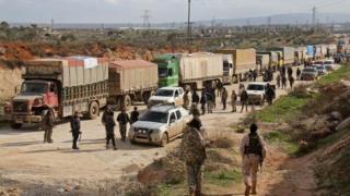 Fighters stand near a convoy of vehicles carrying UN food and medical aid on the outskirts of the rebel-besieged Kefraya. Photo: 14 March 2017