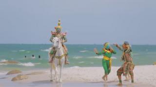 A still from the vide showing the characters on the beach, with one on a horse