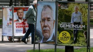 A man walks between posters of Norbert Hofer (left) and Alexander Van der Bellen in Vienna, 19 May