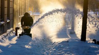 Snow is cleared along a street in the Upper West Side neighborhood of New York Sunday, Jan. 24, 2016