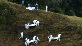 Rescue workers carry the bodies of victims of an airplane that crashed in a mountainous area outside Medellin, Colombia, Tuesday, Nov. 29, 2016
