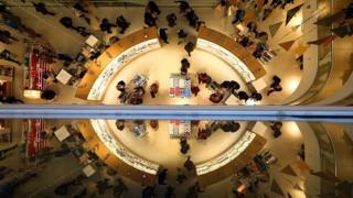 Customers are reflected as they shop in a John Lewis department store