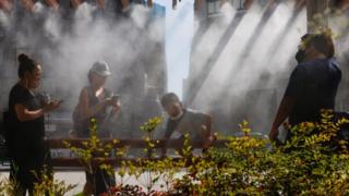 People take a break under a cooling mist