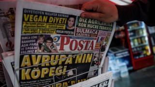 This picture taken in Istanbul on March 13, 2017 shows a man selecting a newspaper bearing a headline concerning diplomatic tensions between Turkey and The Netherlands, which translates as ""Dogs of Europe" in Istanbul on March 13, 2017