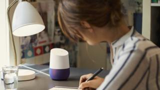 Woman with Google Home speaker on desk