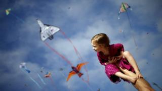 Madeleine Klonoski, 2, sits on her father"s leg at a kite festival in Redondo Beach, California, United States, March