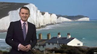Matt Taylor stands in front of a coastal photo