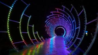A-spiral-of-multicoloured-light-with-a-walkway-running-through-it.