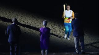 Sally Pearson carries the baton to the stage to be received by Prince Charles.