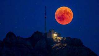 The blood moon rises behind the Saentis (2502m) Alpstein, Canton of Appenzell, Switzerland.