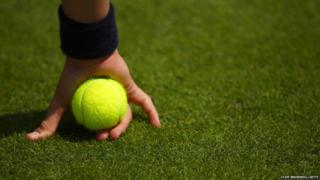 A ball boy holds a ball